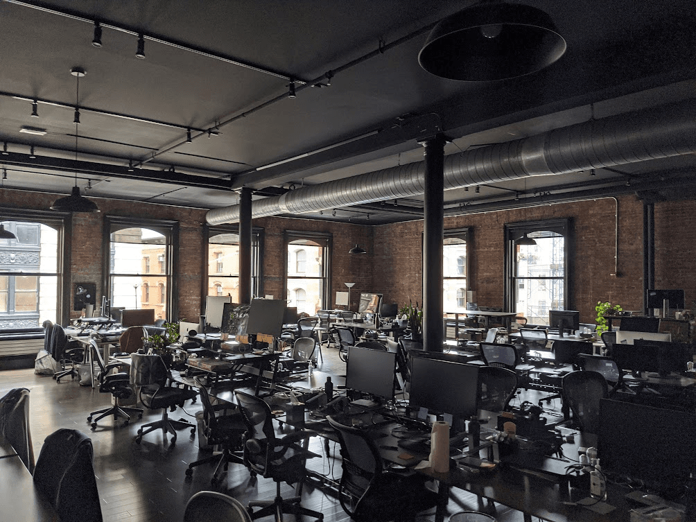 The Codecademy office on Prince Street in NYC — exposed brick, columns, and open desks under tall arched windows